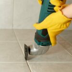 Homeowner using device to help remove grout from tile.