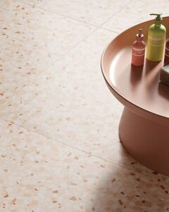 Pink bowl of cosmetics set on beige speckled tiles