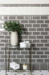 A glass bathroom rack with plant and towels in front of Adex USA tiled wall