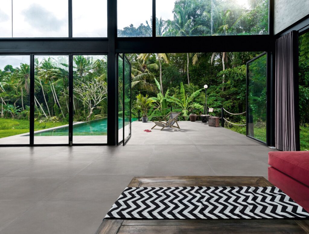Glass indoor area overlooking pool that covered in concrete tile
