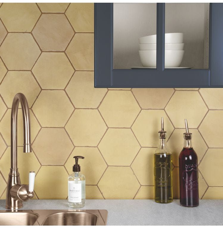 honey yellow hexagon tile backsplash in bathroom with grey mirrors and stainless steel faucets