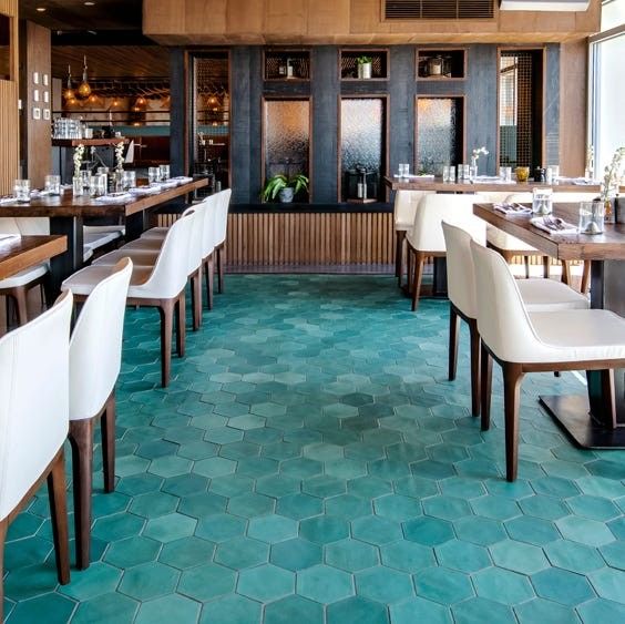 restaurant setting with blue hexagon tile floor and white bar stools