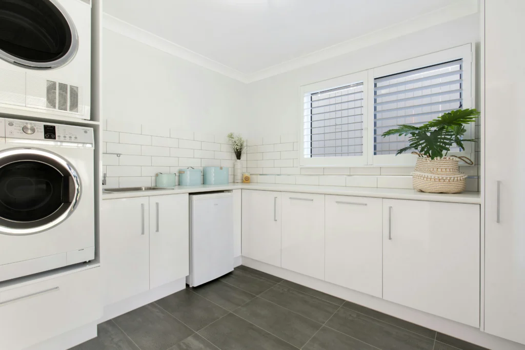 Modern white laundry room with gray tile floor