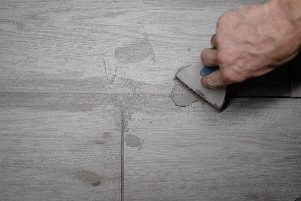 Homeowner regrouting tile on floor.