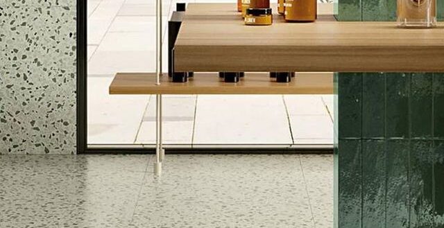 Speckled tile flooring and walls around a large window and floating bar