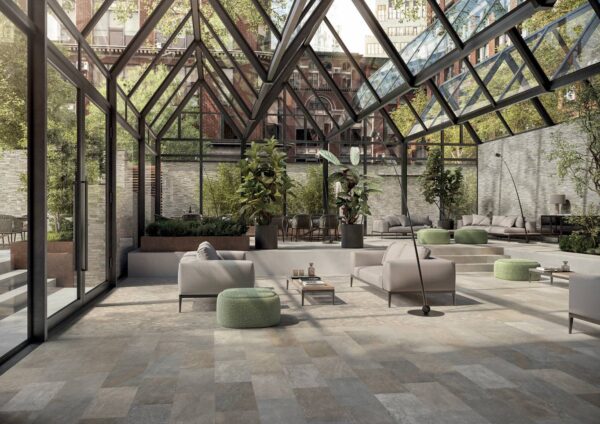 Large modern lounge with a glass roof, stylish furniture, indoor greenery, and variegated slate tile floors.