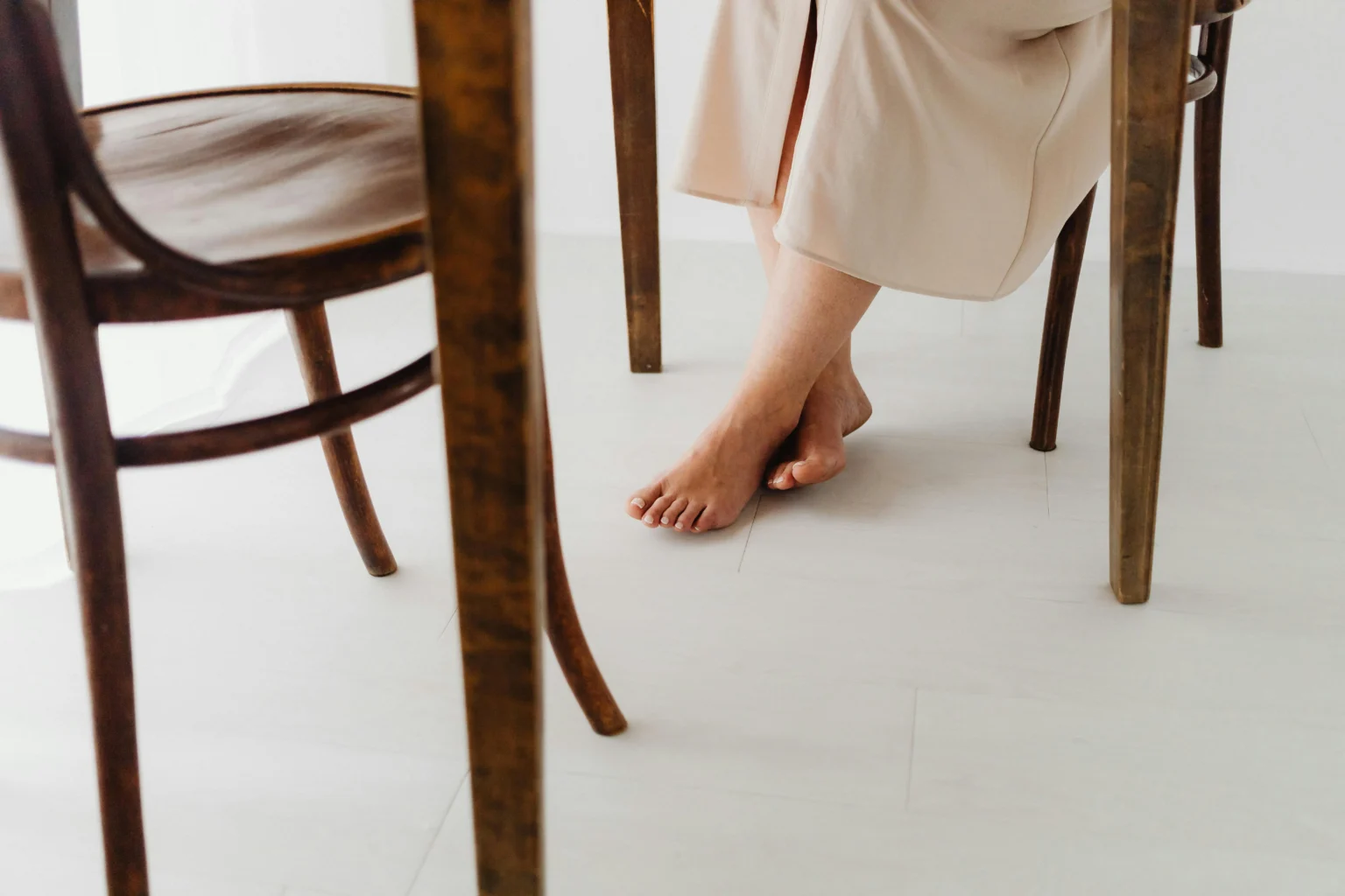 Woman sitting at a table with bare feet on a white tile floor